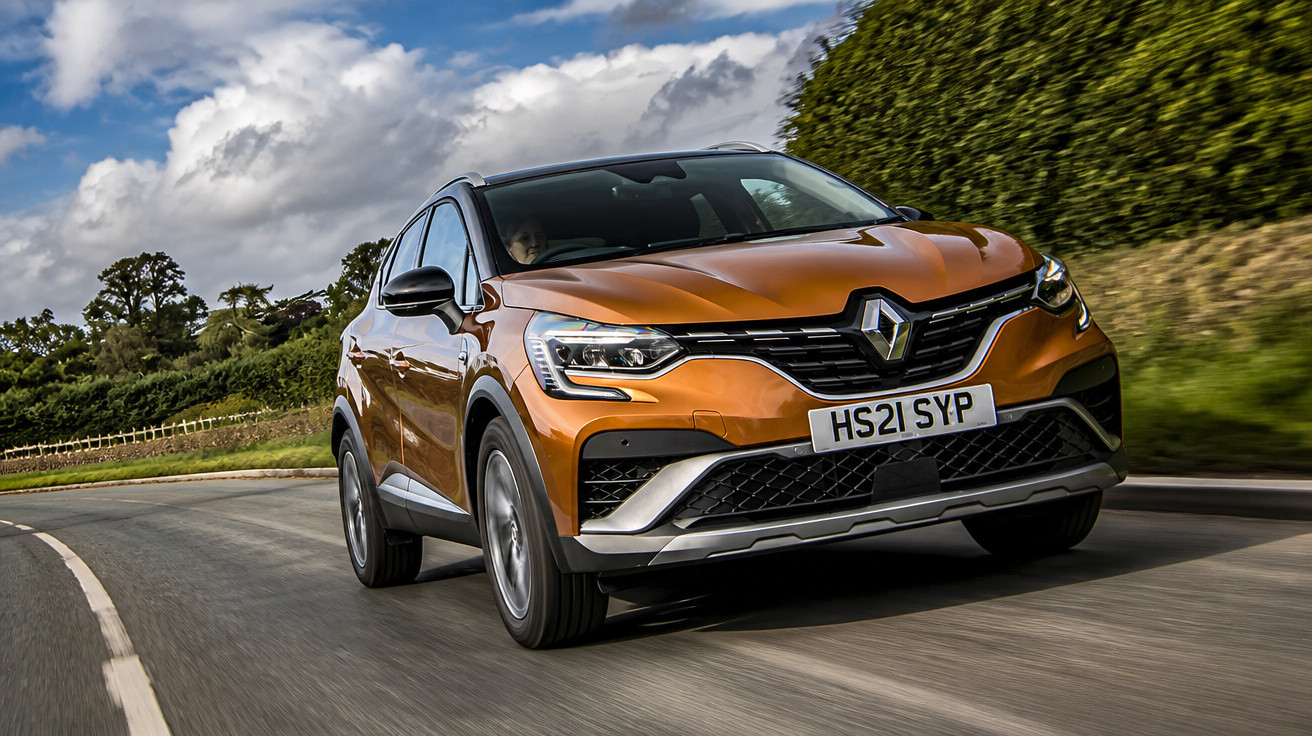 Carro SUV Renault Laranja a circular numa estrada rodeada de vegetação e céu parcialmente nublado.