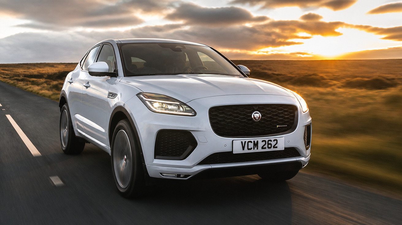Carro SUV branco Jaguar a circular numa estrada reta com céu ao pôr do sol.