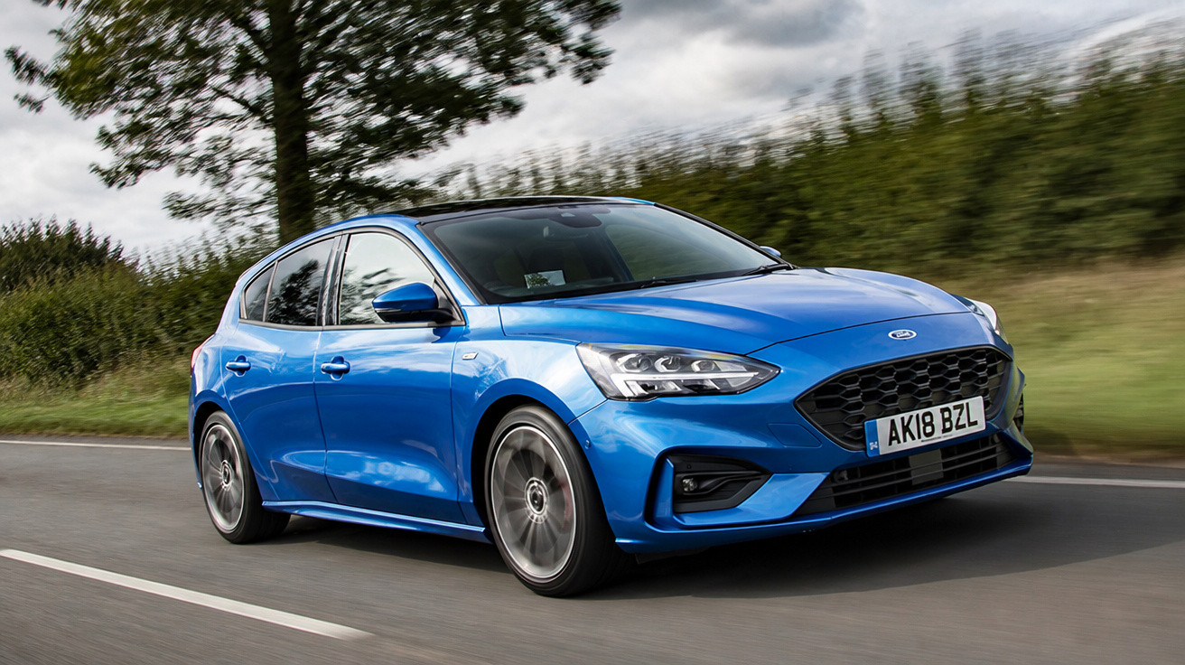 Carro azul desportivo a circular numa estrada rodeada de árvores e vegetação verde.