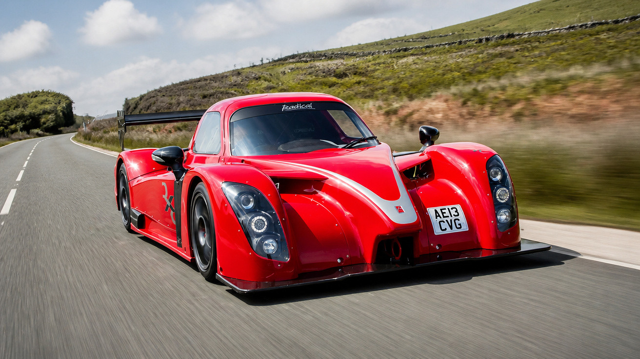 Carro desportivo vermelho Radical a alta velocidade numa estrada rural sob céu nublado.