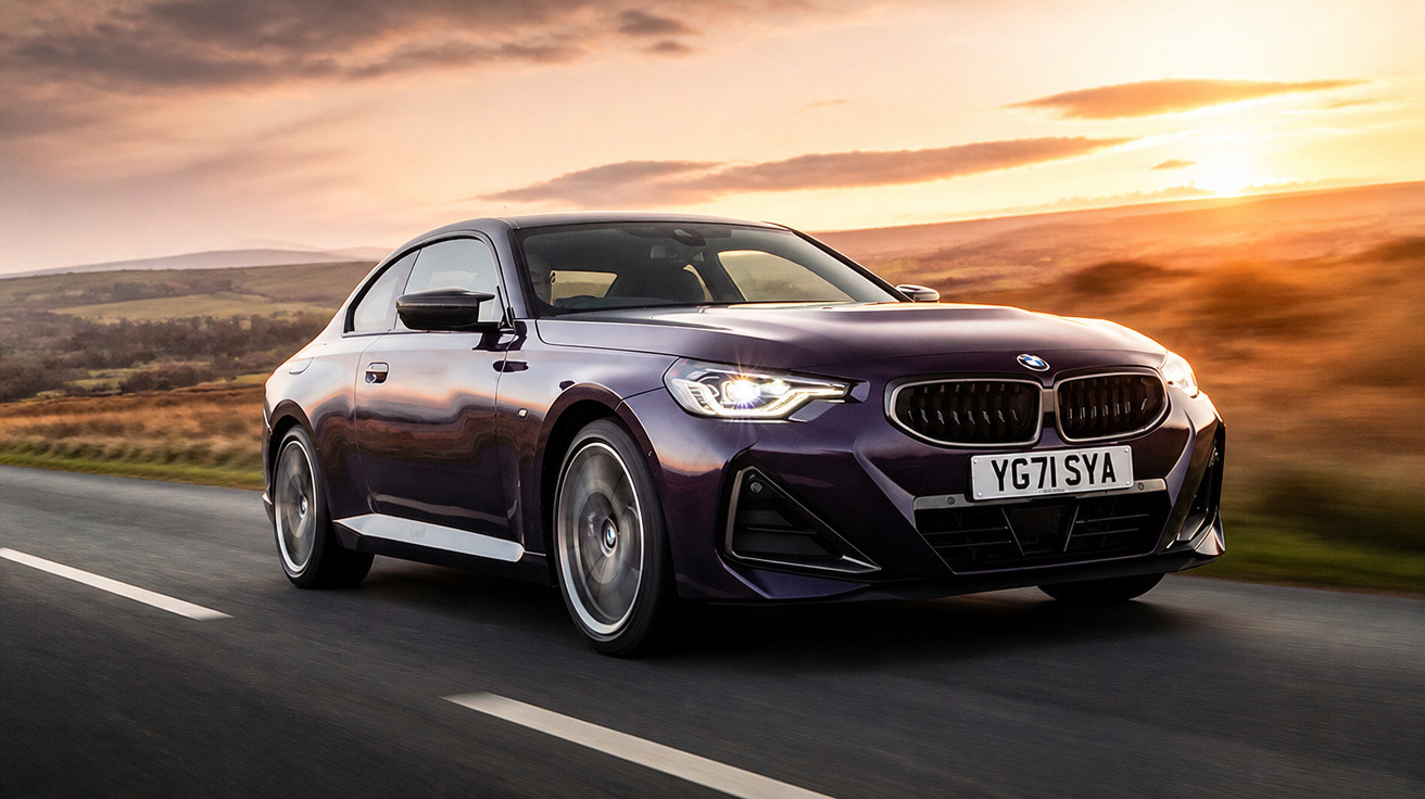 Carro desportivo BMW roxo a circular numa estrada rural ao pôr do sol.